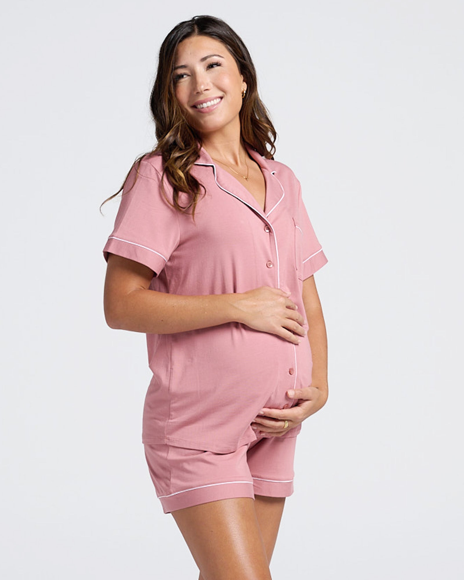 Pregnant Woman wearing a pink maternity pajama set with white binding and open front