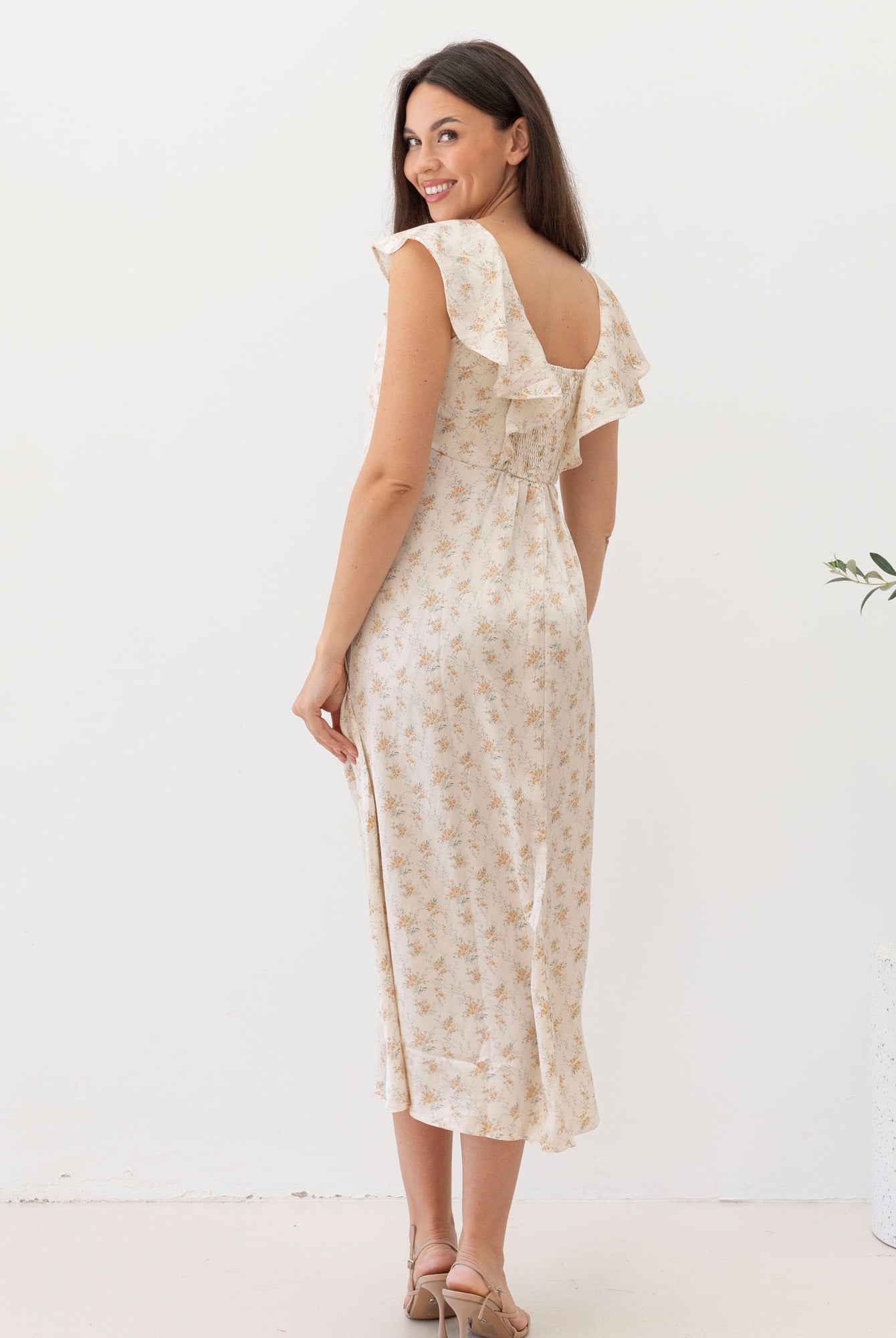 Woman wearing a floral dress with ruffled sleeves on a white background