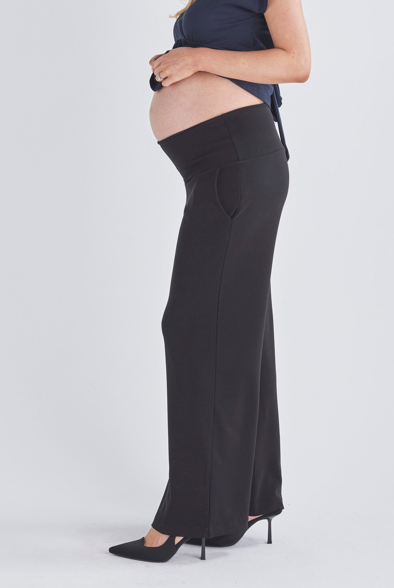 A Pregnant Woment Wearing Elodie Wide Leg Maternity Black Work Pant in Ponti from Angel Maternity Australia