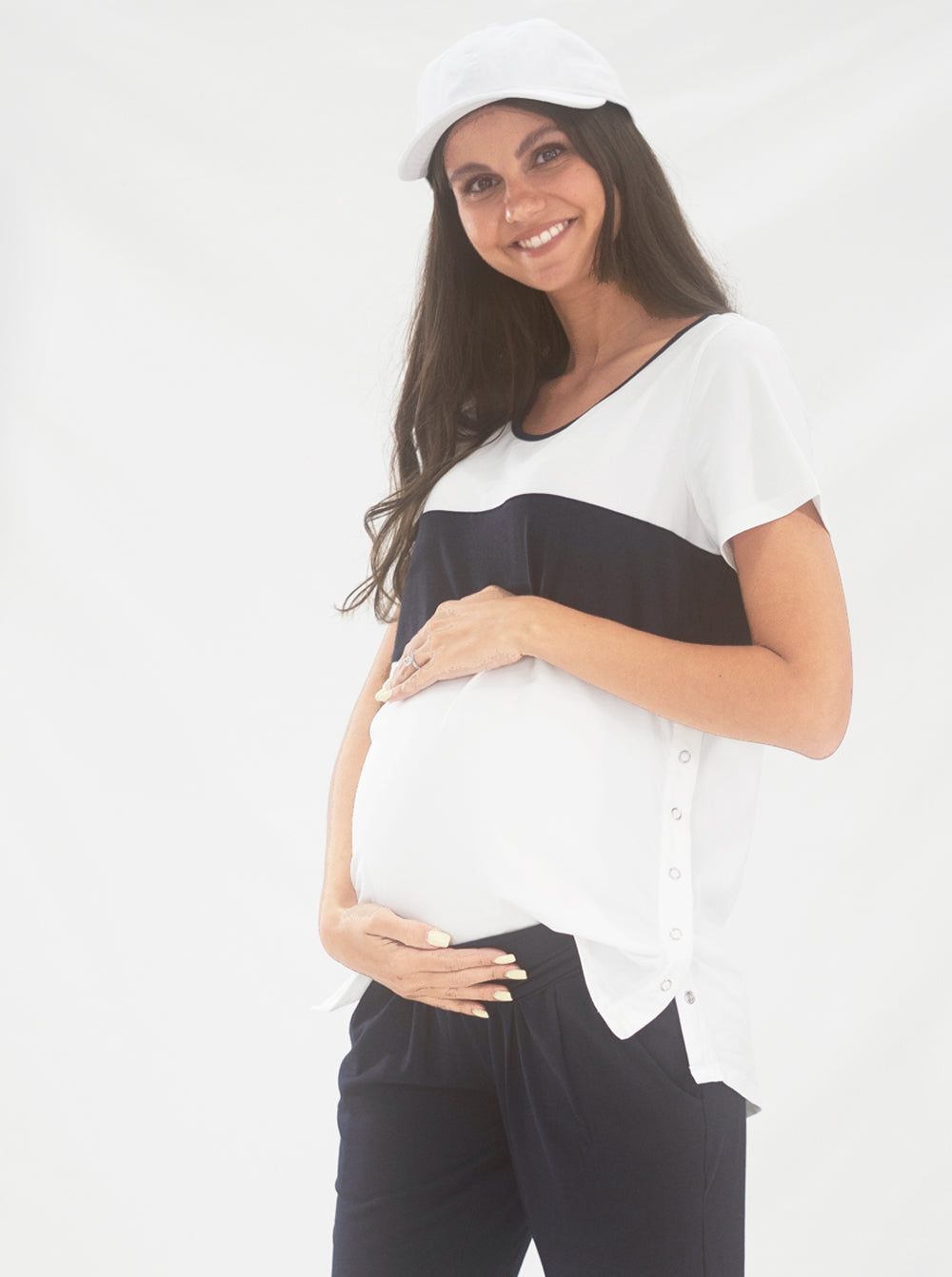 Main view - A young pregnant woman in Maternity and Nursing T-Shirt in Navy and White with Side Zip touching her bump & smiling (6663267844190)