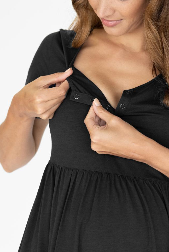 A young pregnant woman in Short Sleeve Tiered Mini Black Maternity Dress showing opening for easy access for breastfeeding (4827569684574)