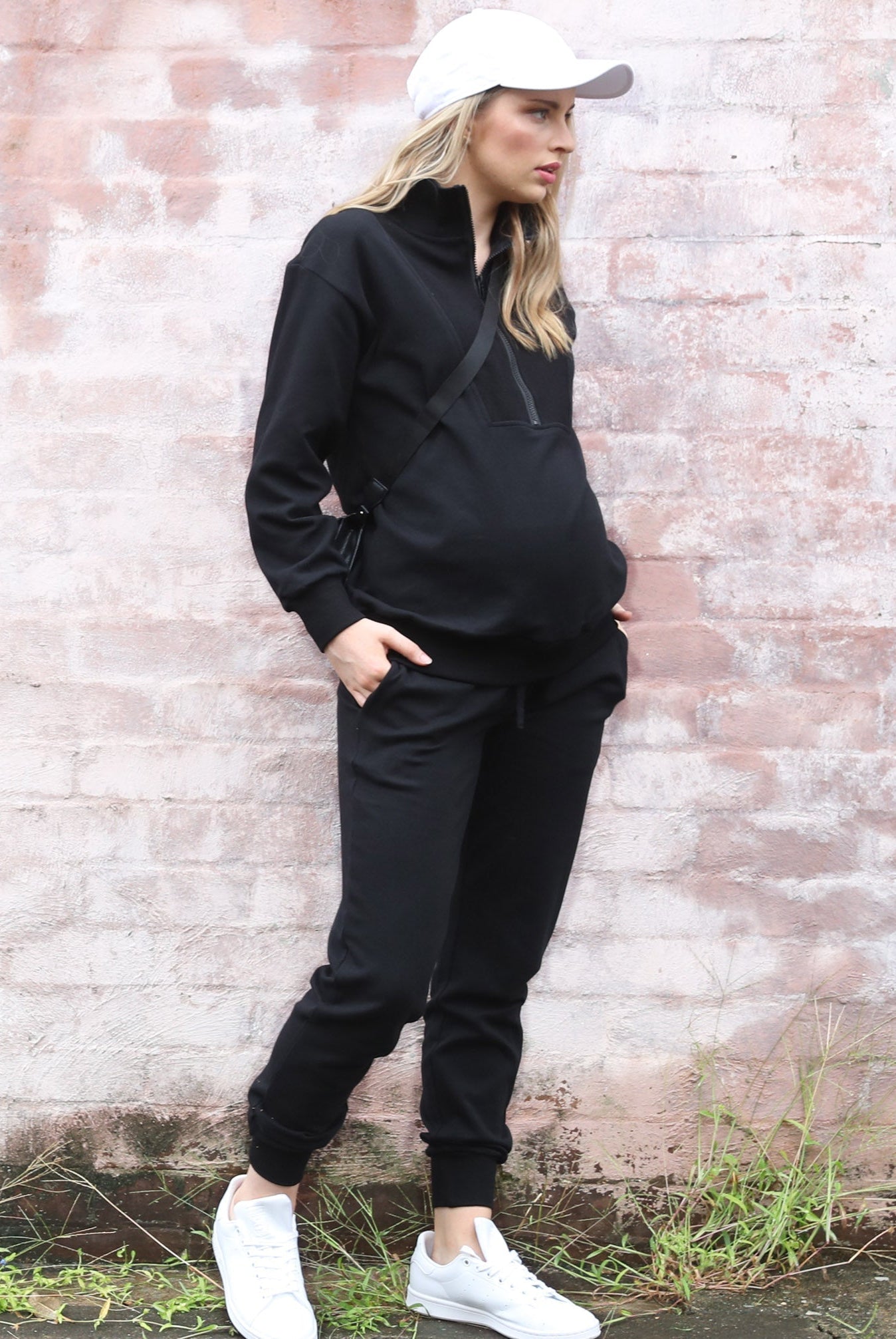 Side view - A pregnant woman in 2-Piece Calla zip front black Maternity Tracksuit Set walking (6718252810334)