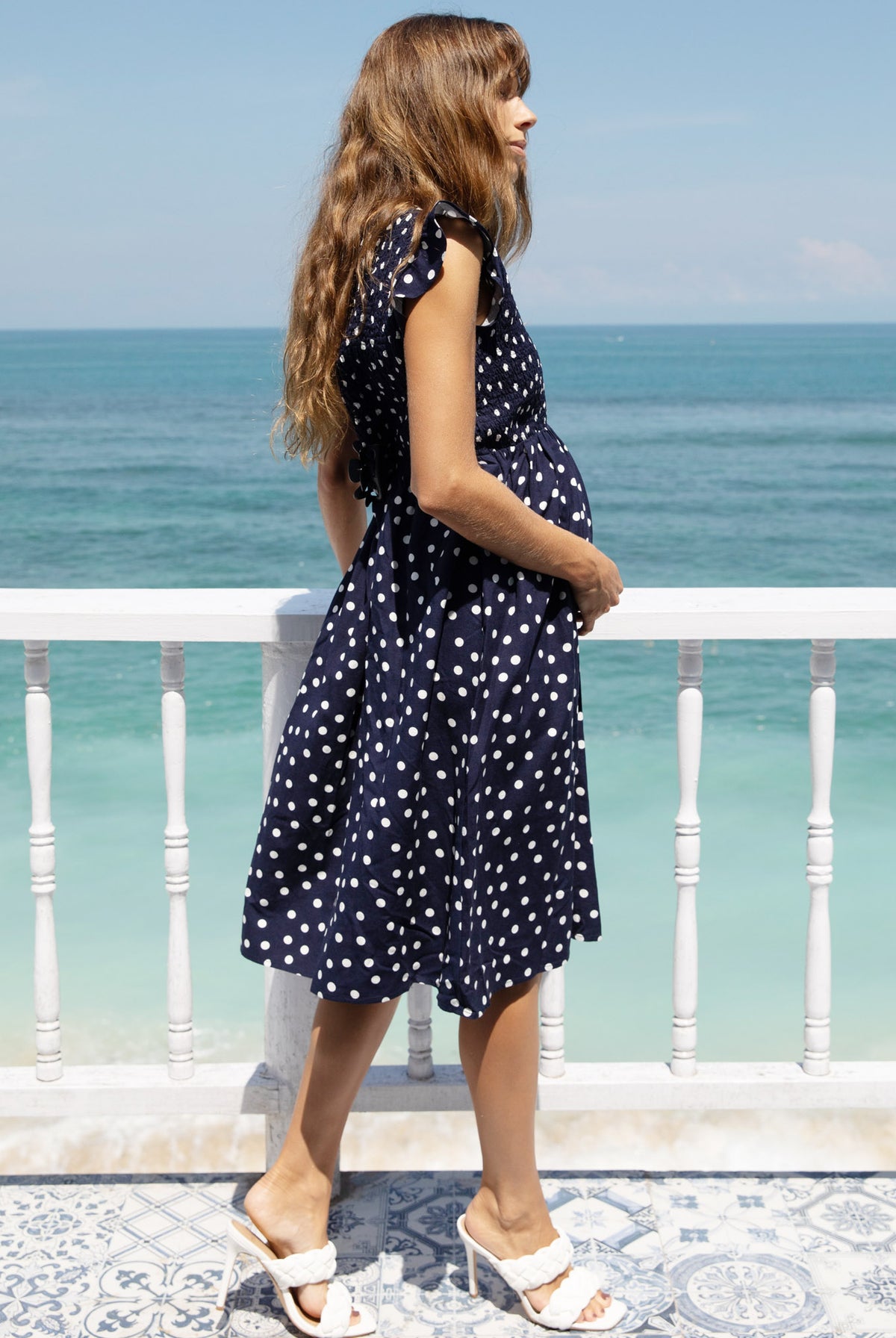 A woman in linen maternity spot dress, side (6681442353246)