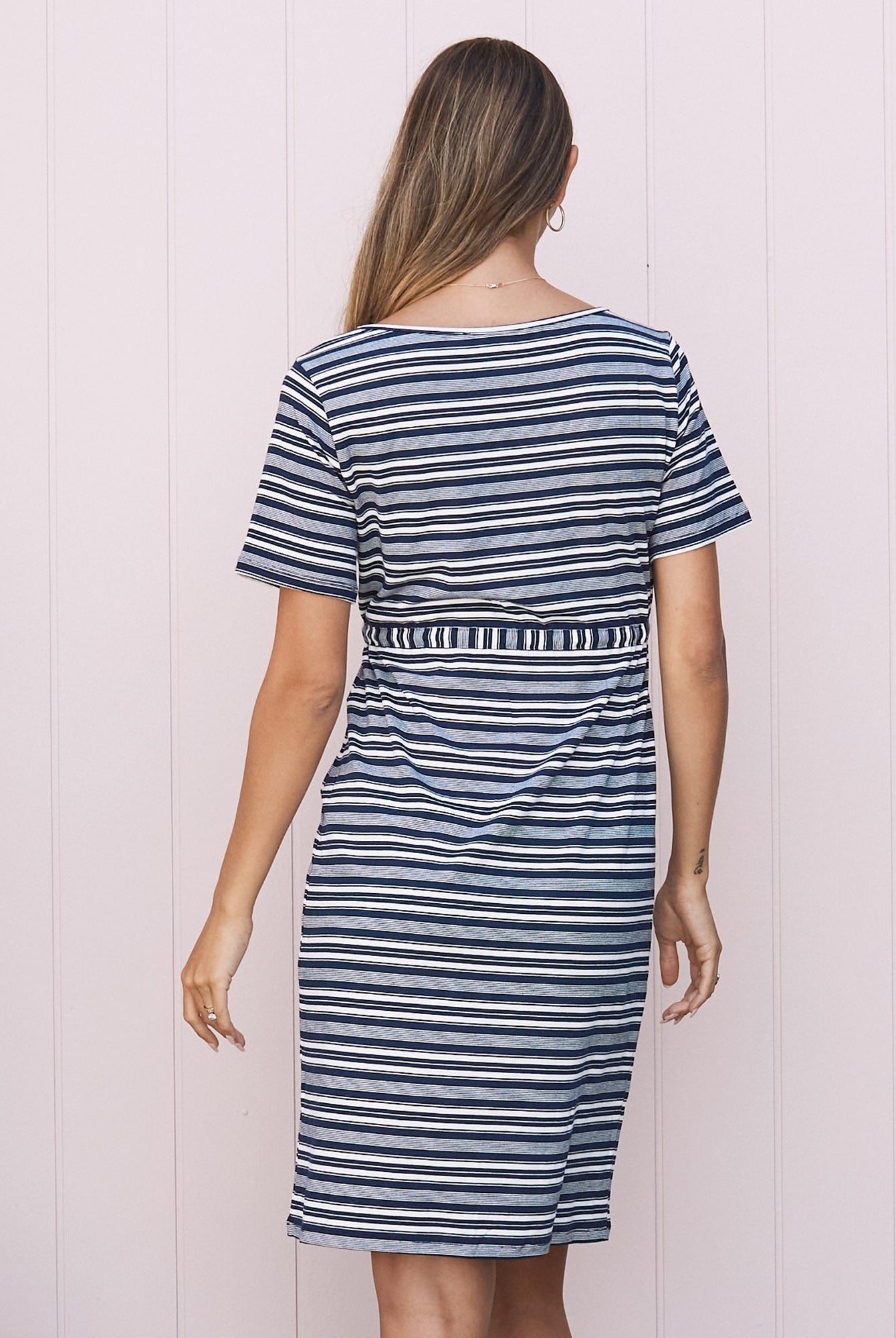 Back View - A pregnant Woman in Maternity Short Sleeve Drawstring Dress in Navy & White Stripes