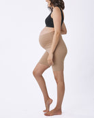 A pregnant woman wearing beige maternity comfort cotton bike shorts with a black top.