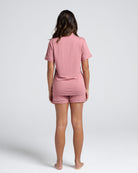 Person wearing a pink  maternity pajama set on a white background