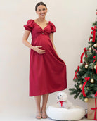 Woman in a red dress standing next to a Christmas tree with a white dog on a white background