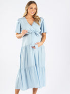 Front view - A pregnant woman in Blue Baby Shower Maxi Maternity Dress touching her bump & smiling (6659011510366)