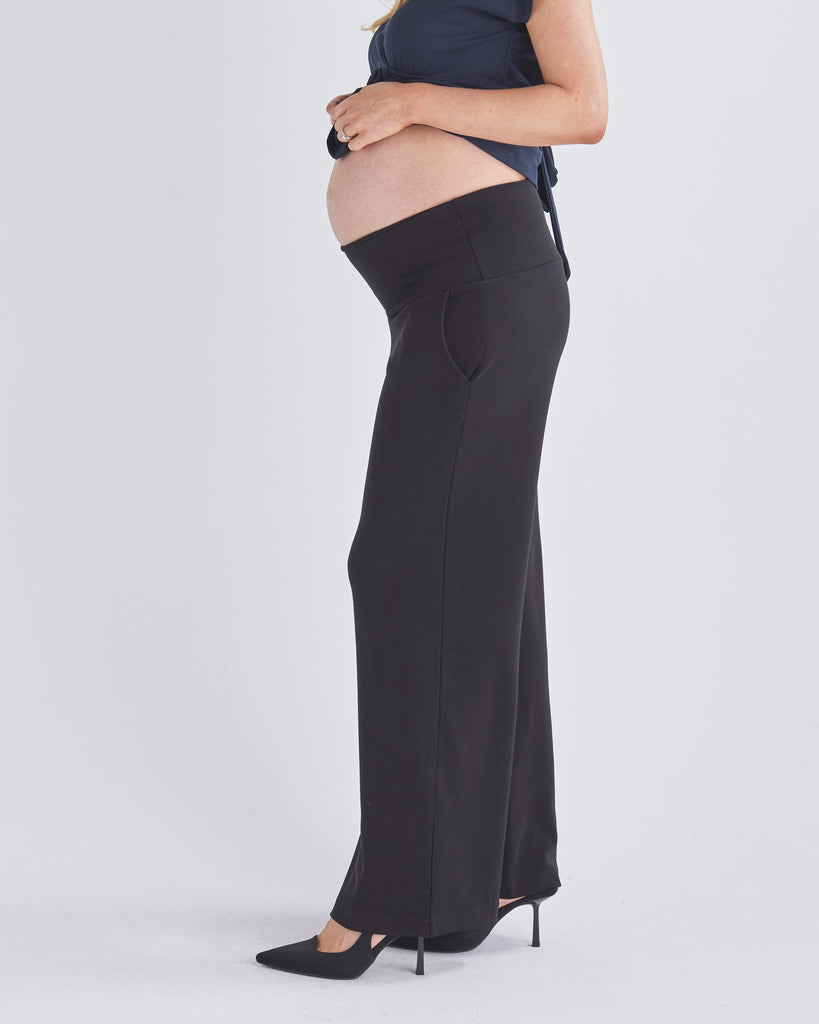 A Pregnant Woment Wearing Elodie Wide Leg Maternity Black Work Pant in Ponti from Angel Maternity Australia