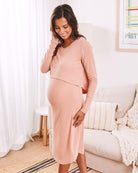 a young pregnant women  wearing maternity nursing friendly loungewear dress in pink 
