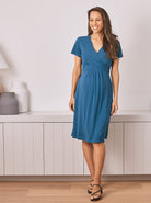 A Pregnant Woman in Maternity Crossover Neckline Tie Back Jersey Work Dress in Teal Blue from Angel Maternity
