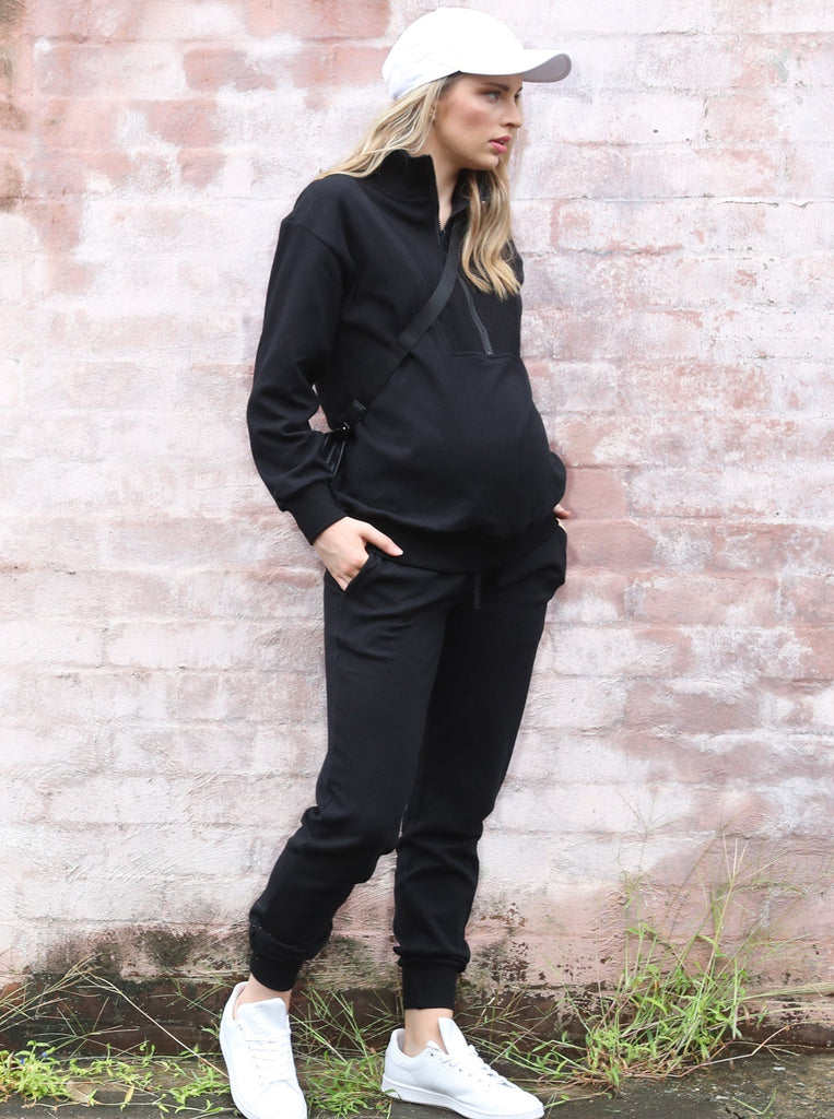 Side view - A pregnant woman in 2-Piece Calla zip front black Maternity Tracksuit Set walking (6718252810334)