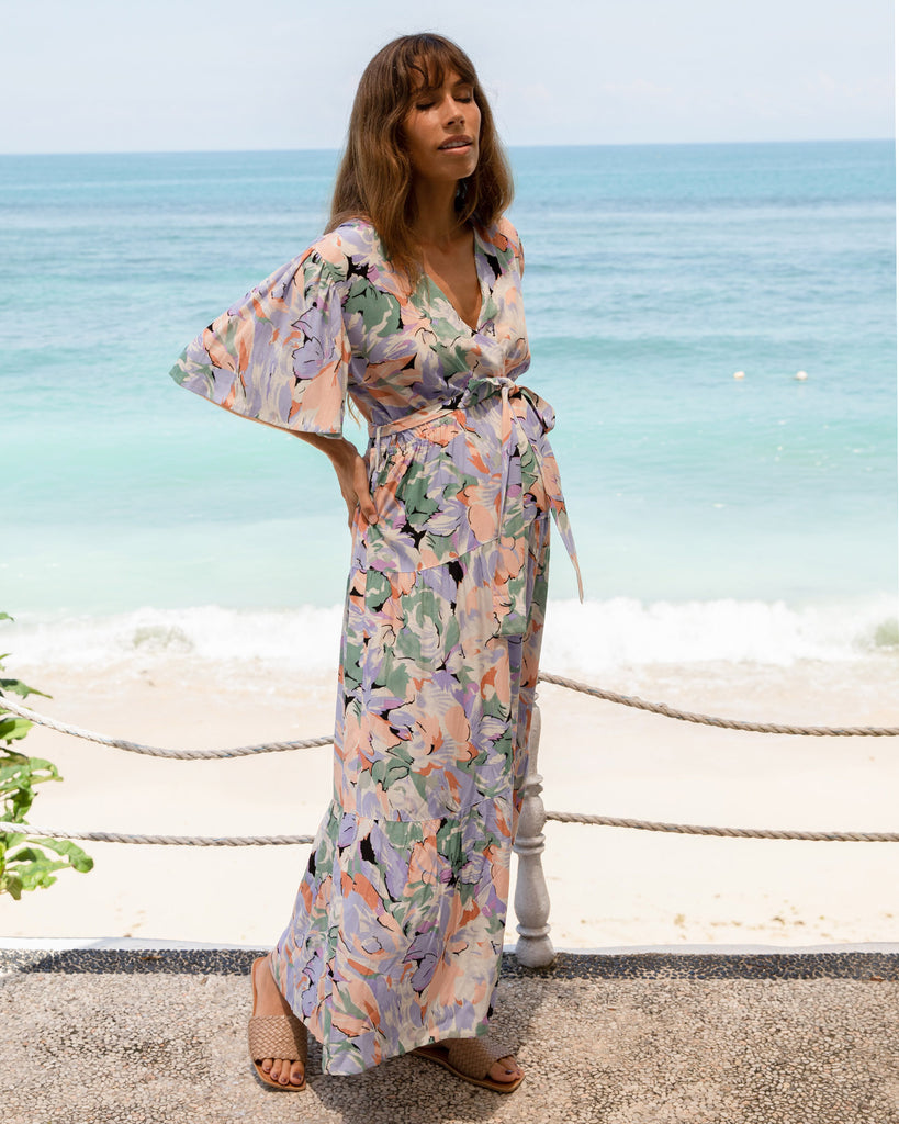 A woman in floral lavender maternity baby shower dress, on the beach (6672554033246)