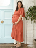 A woman in rust maternity dress, side (6677167865950)